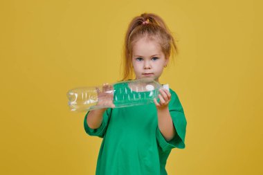 Çevreye önem vermek. Küçük kız geri dönüşüm için ayrı bir plastik çöplük. Parlak renkli stüdyo arkaplanı