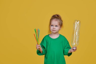 Çevreye önem vermek. Küçük kız geri dönüşüm için ayrı bir plastik çöplük. Parlak renkli stüdyo arkaplanı
