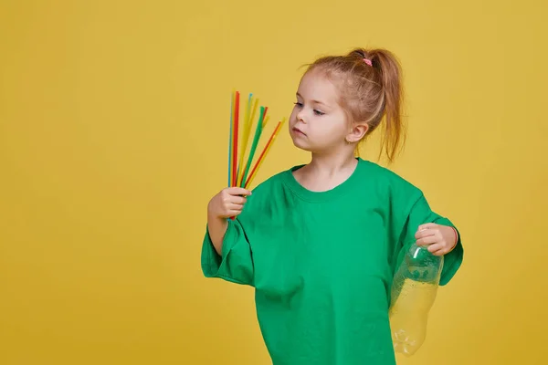 Caring for the environment. Little girl is separate plastic trash to recycle. Bright color studio background