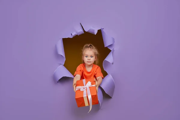 Cute Little Child Girl Breaks Colored Purple Paper Wall Gift — Stock Photo, Image