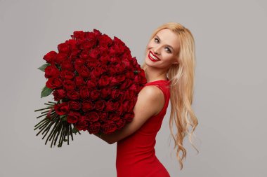 Bir buket kırmızı gül çiçekli güzel romantik kadın. Kırmızı dudaklar. Sevgililer Günü veya 8 Mart Tatil Sınır Tasarımı. Gri nötr arka planda modaya uygun kız modelinin portresi