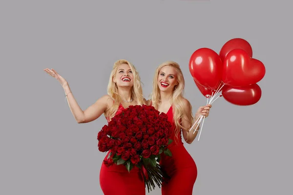 Dwie Szczęśliwe Młode Bliźniaczki Wielkim Bukietem Czerwonych Róż Czerwonymi Balonami — Zdjęcie stockowe