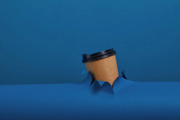 男性的手拿着一杯咖啡穿过撕破的经典蓝皮书背景 得到能量提升 热饮料在外卖包 — 图库照片