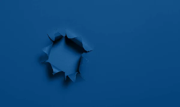 Breakthrough paper hole with blue textured background. Mockup for designer card. Empty copy space for text