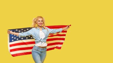 American girl. Happy young woman in denim clothes holding USA flag on yellow background. Banner. Copy space for text. football fan