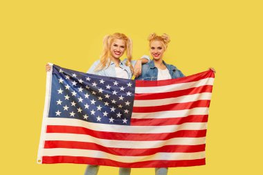 Amerikalı kızlar. Sarı arka planda Usa bayrağı taşıyan kot elbiseli mutlu genç kadınlar. futbol hayranı