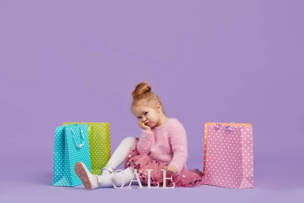 Retrato Uma Menina Pequena Feliz Fundo Roxo Segurando Sacos Compras — Fotografia de Stock