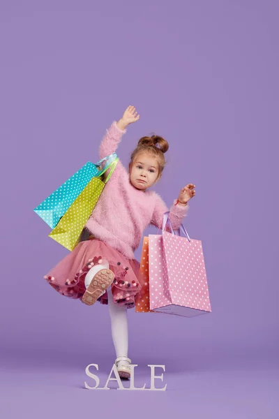 Porträt Eines Glücklichen Kleinen Mädchens Auf Lila Hintergrund Mit Einkaufstaschen — Stockfoto