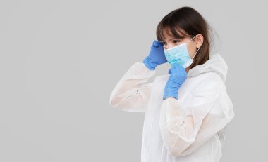 Asyalı kadın koruyucu bir maske ve takım elbise giyer. Grip, ebola, tüberküloz ve virüsten korunuyor. Biyolojik tehlikeye karşı kişisel koruma ekipmanları. 