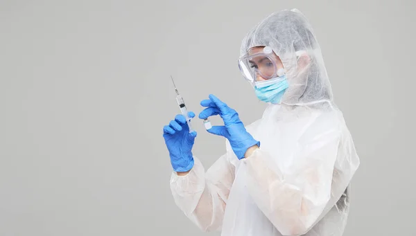 Biological hazard. Epidemic of the Chinese coronavirus. An asian woman in a protective suit and mask holds an injection syringe and vaccine. Vaccine from, flu, coronavirus, ebola, TB.