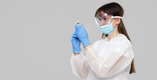 Biological hazard. Epidemic of the Chinese coronavirus. An asian woman in a protective suit and mask holds an injection syringe and vaccine. Vaccine from, flu, coronavirus, ebola, TB.