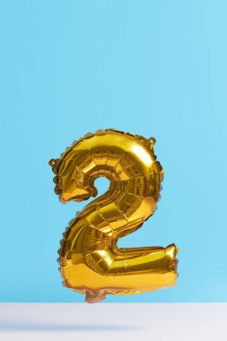 Mavi arka planda rakamlar şeklinde altın folyo balonu. Yükseltme etkisi