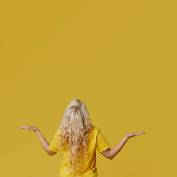 年轻快乐的女人举手 把他的手伸向两边 上面是一个空的地方 在黄色的背景上放着文字和题词 — 图库照片