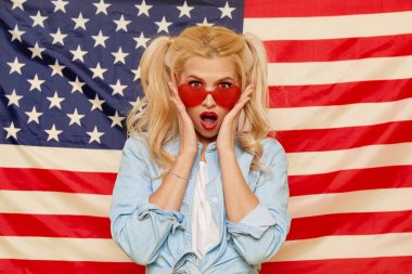 American girl. Portrait of Happy of young surprised woman on USA flag  background. Funny human face. Patriotism concept