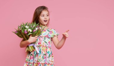 Şirin gülümseyen kız elinde bir buket bahar çiçeği, pembe arka planda izole laleler tutuyor. Küçük kız annesine bir buket verir. Metin için alanı kopyala. 