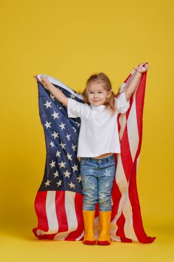 Vatansever bayram. Mutlu çocuk, sarı stüdyo geçmişinde Amerikan bayrağı olan sevimli küçük kız. Usa 4 Temmuz 'u kutluyor, Bağımsızlık Günü.