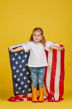 Vatansever bayram. Mutlu çocuk, sarı stüdyo geçmişinde Amerikan bayrağı olan sevimli küçük kız. Usa 4 Temmuz 'u kutluyor, Bağımsızlık Günü.