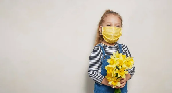 戴着防护口罩的小女孩手里拿着一束黄色的春花 大流行病全球检疫概念 — 图库照片