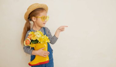 Lastik botunda sarı çiçekleri olan hasır şapkalı küçük bir kız çocuğu. Annemin küçük yardımcısı bahçedeydi. Metin için alanı kopyala