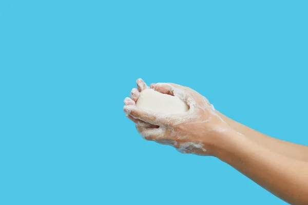 Hand hygiene concept. Female hands are holding antibacterial soap with foam on a blue background. Hand antiseptic during the coronovirus pandemic