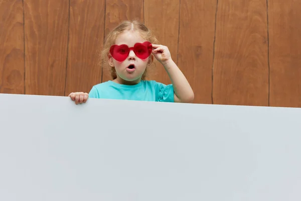 Piccola Bambina Sorridente Bicchieri Forma Cuore Piedi Dietro Pannello Bianco — Foto Stock