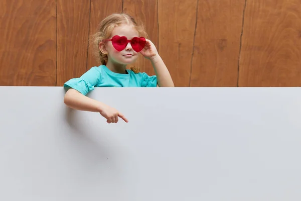 Piccola Bambina Sorridente Bicchieri Forma Cuore Piedi Dietro Pannello Bianco — Foto Stock
