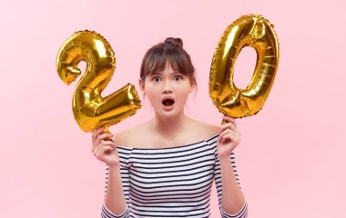 Asya uyruklu genç bir kadın elinde şişme balonlar tutuyor. Yüzde 20 oranında. İndirim, satış ve nakit para kavramı. Pembe stüdyo arka planı