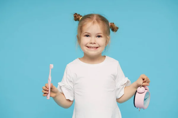 口腔卫生 是时候刷牙了小女孩用牙刷刷牙 看着蓝色背景的相机 — 图库照片