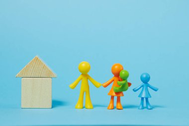 Mavi arka planda meçhul aile. Ev konseptinde kal. Çocuk mozaiğinden evin yakınındaki insanların çok renkli figürleri