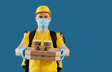 Koruyucu maskeli ve tıbbi eldivenli kurye paket yiyecek ve kahve getiriyor. Teslimat servisi karantina altında. Metin için alanı kopyala
