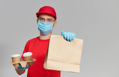Koruyucu maskeli ve tıbbi eldivenli kurye paket yiyecek ve kahve getiriyor. Teslimat servisi karantina altında. Metin için alanı kopyala