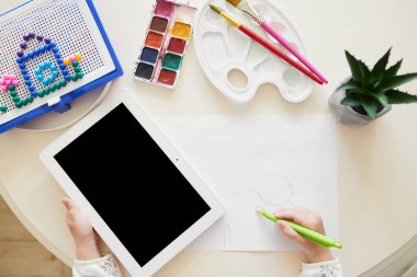 Çevrimiçi Eğitim kavramı. Akıllı küçük kız evde uzaktan öğrenmek için tablet kullanıyor. Üst görünüm