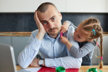 Babam karantina sırasında dizüstü bilgisayarla evde çalışıyordu. Küçük kız gürültü yapıyor ve babasının dikkatini mutfak ofisinden başka yöne çekiyor.