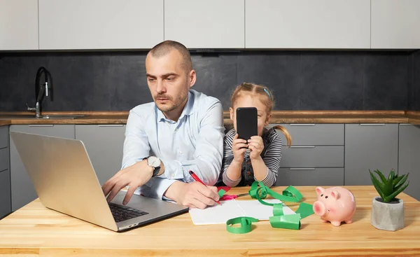 Father Working from home on laptop during quarantine. Young father does homework with his little daughter