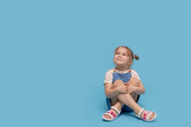 Uluslararası Çocuklar Günü 'nde. Mavi arka planda izole edilmiş, şaşırmış çocuk portresi. Metin için boş alan. Bebek ürünleri reklamı. 