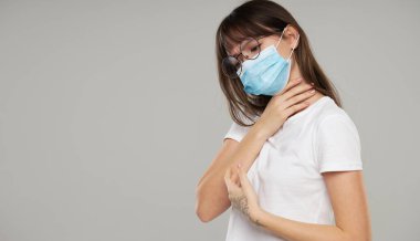 Yüz koruma maskesi takan Asyalı kadın gri stüdyo geçmişinden rahatsız. Uzayı metin için kopyala. Grip ve koronavirüs salgınına karşı ilk savunma.