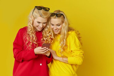 3D gözlüklü genç mankenler internetten cep telefonu uygulamasından film izliyorlar. Sarı arkaplanda izole edilmiş