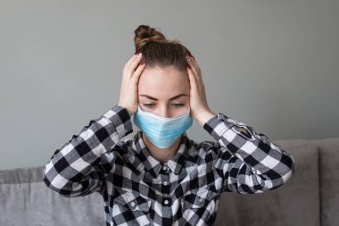 Onu virüsten korumak için tıbbi maskeli bir kız. Koronavirüs salgını. Maskeli kadın ayakta. İnsanlar Corona 'nın yayılmasını engellemek için hastaneye yatırılıyor, teşhis konuyor ve genellikle karantinaya alınıyor..