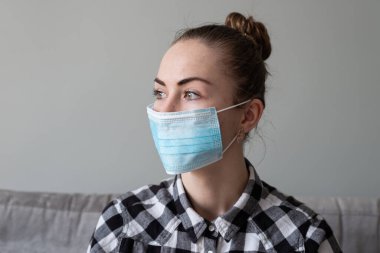 Onu virüsten korumak için tıbbi maskeli bir kız. Koronavirüs salgını. Maskeli kadın ayakta. İnsanlar Corona 'nın yayılmasını engellemek için hastaneye yatırılıyor, teşhis konuyor ve genellikle karantinaya alınıyor..