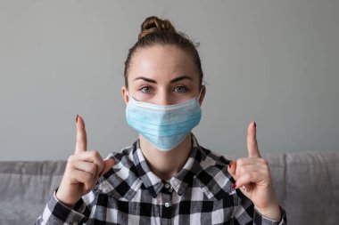 Onu virüsten korumak için tıbbi maskeli bir kız. Koronavirüs salgını. Maskeli kadın ayakta. İnsanlar Corona 'nın yayılmasını engellemek için hastaneye yatırılıyor, teşhis konuyor ve genellikle karantinaya alınıyor..