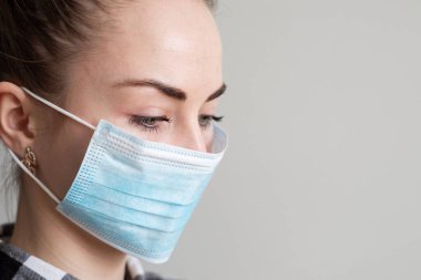 Onu virüsten korumak için tıbbi maskeli bir kız. Koronavirüs salgını. Maskeli kadın ayakta. İnsanlar Corona 'nın yayılmasını engellemek için hastaneye yatırılıyor, teşhis konuyor ve genellikle karantinaya alınıyor..