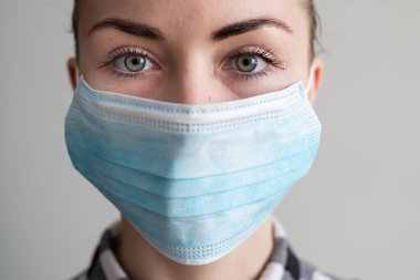 Onu virüsten korumak için tıbbi maskeli bir kız. Koronavirüs salgını. Maskeli kadın ayakta. İnsanlar Corona 'nın yayılmasını engellemek için hastaneye yatırılıyor, teşhis konuyor ve genellikle karantinaya alınıyor..