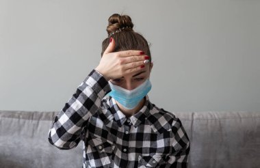 Onu virüsten korumak için tıbbi maskeli bir kız. Koronavirüs salgını. Maskeli kadın ayakta. İnsanlar Corona 'nın yayılmasını engellemek için hastaneye yatırılıyor, teşhis konuyor ve genellikle karantinaya alınıyor..