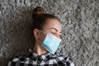 Onu virüsten korumak için tıbbi maskeli bir kız. Koronavirüs salgını. Maskeli kadın ayakta. İnsanlar Corona 'nın yayılmasını engellemek için hastaneye yatırılıyor, teşhis konuyor ve genellikle karantinaya alınıyor..