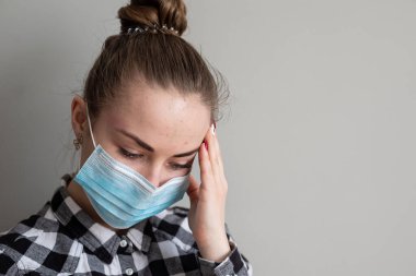Onu virüsten korumak için tıbbi maskeli bir kız. Koronavirüs salgını. Maskeli kadın ayakta. İnsanlar Corona 'nın yayılmasını engellemek için hastaneye yatırılıyor, teşhis konuyor ve genellikle karantinaya alınıyor..