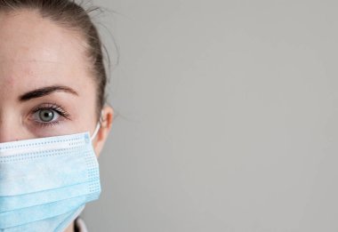 Onu virüsten korumak için tıbbi maskeli bir kız. Koronavirüs salgını. Maskeli kadın ayakta. İnsanlar Corona 'nın yayılmasını engellemek için hastaneye yatırılıyor, teşhis konuyor ve genellikle karantinaya alınıyor..