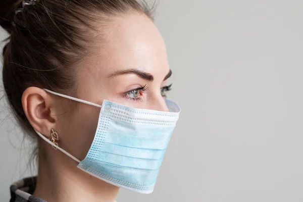 Onu virüsten korumak için tıbbi maskeli bir kız. Koronavirüs salgını. Maskeli kadın ayakta. İnsanlar Corona 'nın yayılmasını engellemek için hastaneye yatırılıyor, teşhis konuyor ve genellikle karantinaya alınıyor..