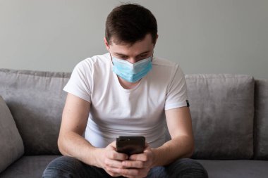 COVID-19 Pandemic Coronavirus, Coronavirus hastalığını yaymak ve cep telefonuyla konuşmak için maske takan adam. SARS-CoV-2 karşısında yüzünde cerrahi maske olan bir adamın portresi.
