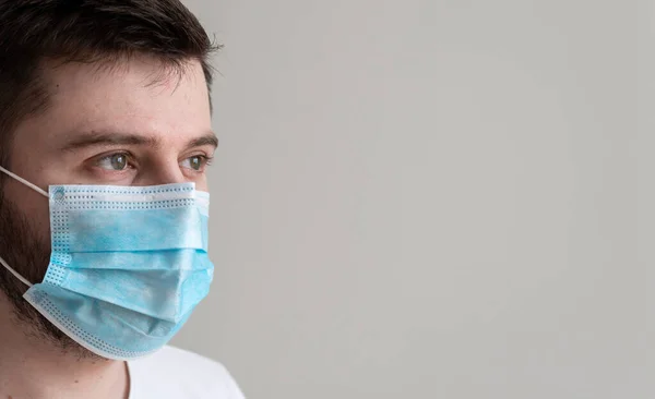 Kameraya Bakan Genç Adam 'ın Yakın Çekimi Gri Geçmişli Cerrahi Maske Giyin