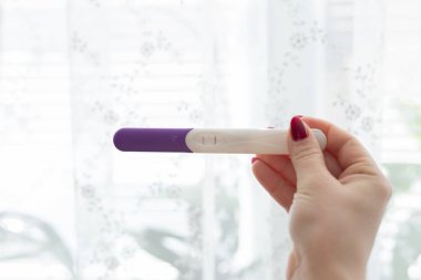 Bulanık arka planda kadın elinde hamilelik testi